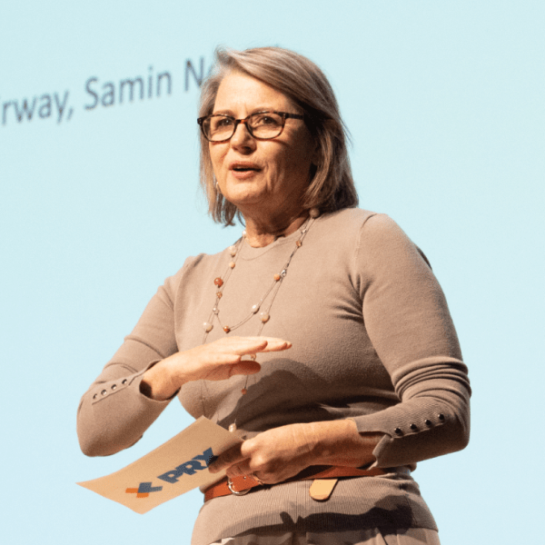 Kerri Hoffman speaking while holding a PRX branded note card in front of a large screen.